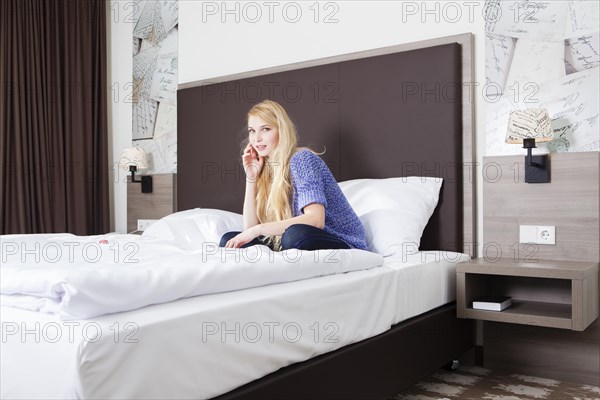 Woman sitting with her laptop on the bed in a hotel room