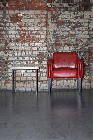 Red armchair in front of an old brick wall