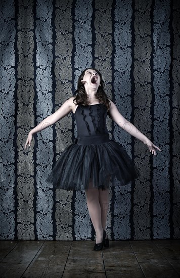 Girl wearing a black ballet dress screaming