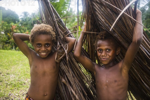 Two young boys carrying palm leaves