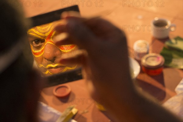 Kathakali dancer applying makeup in preparation for his performance