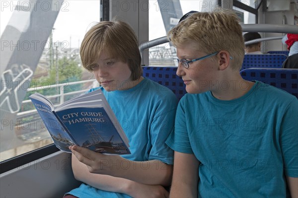 Young people on a language trip read an English travel guide on the train