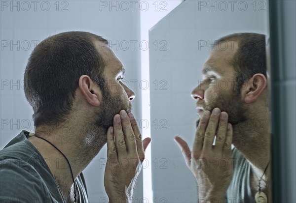 Man with a beard looking into a mirror