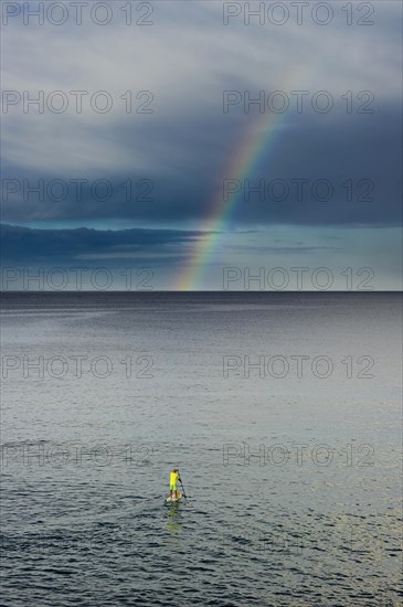 Standing paddler and a rainbow