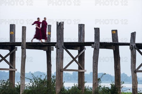 Monks walking on a teak bridge