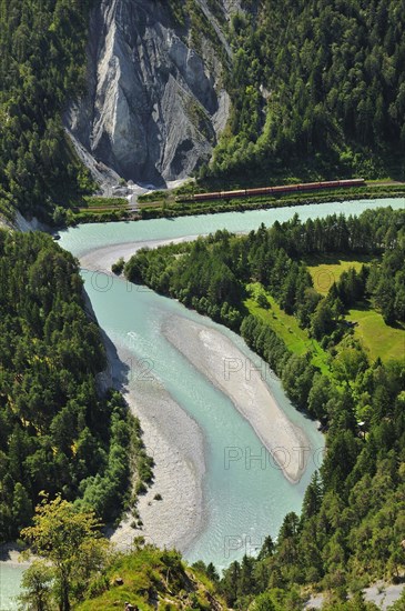 Train of the Rhaetian Railway on the riverbanks of the Vorderrhein