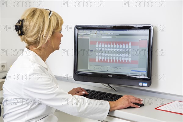 Dental assistant entering a patient's data into the electronic medical record