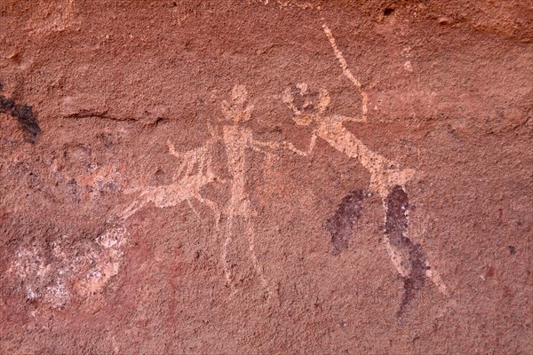 Rock painting of people with dogs