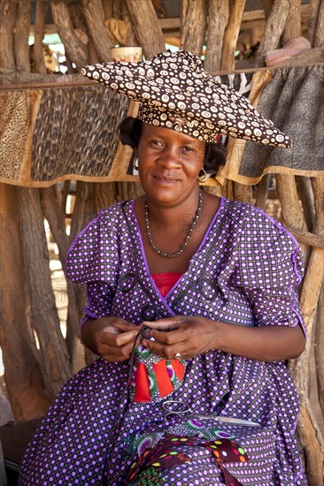 Herero woman with typical headdress sewing souvenirs