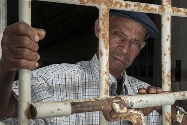 A former prisoner standing behind a door with iron bars