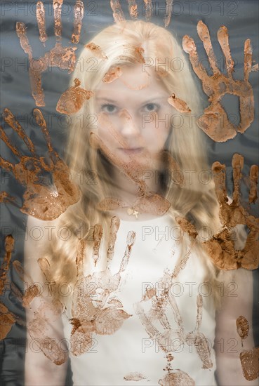 Young woman behind plastic sheet covered with handprints