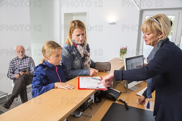 Patients filling in a form at the reception of a dental office