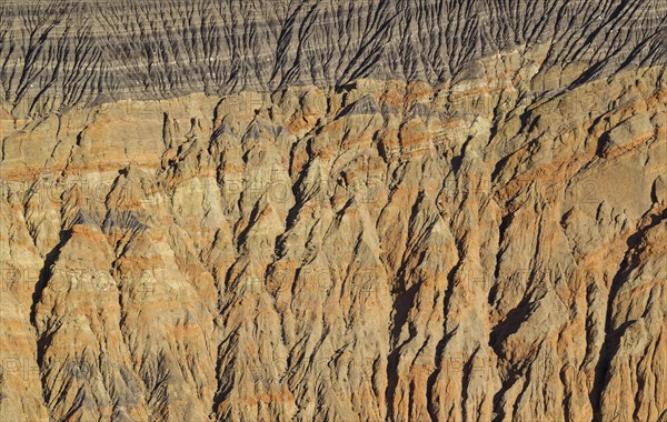 Exposed fissured bedrock of orange-colored conglomerate on the crater wall of Ubehebe Crater