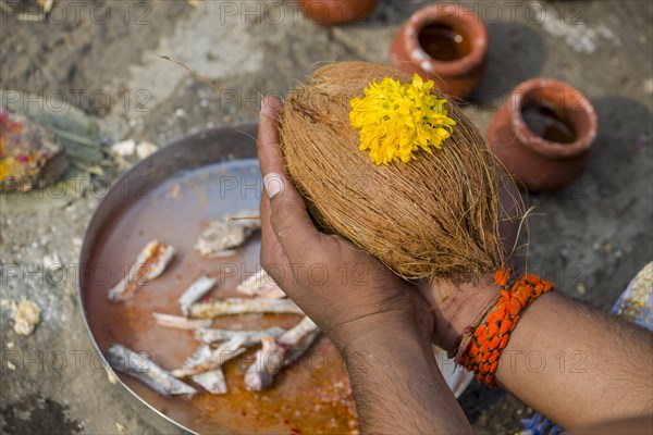 A man is holding a coconut during Dashkriya or Asthi Visarjan