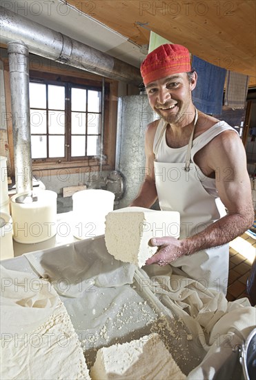 Dairyman cutting the finished cottage cheese into pieces