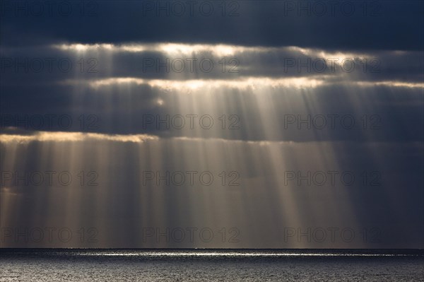 Sun rays shine through dark storm clouds