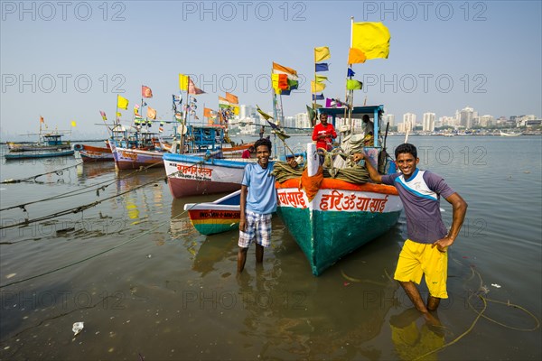 Two fishermen and some fishing boats in front of the skyline of the suburb Churchgate seen across the Back Bay