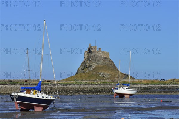 Sailing boats at low tide in the bay off Lindisfarne Castle