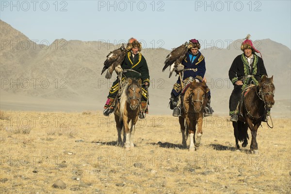 Three Kazakh eagle hunters on their horses on the way to the Eagle Festival in Sagsai