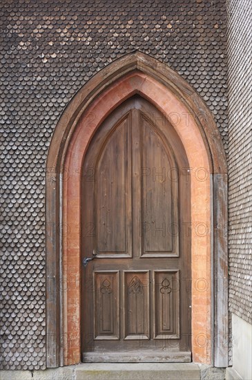 Side entrance with a shingled facade of the neo-Gothic Parish Church of St. Pelagius