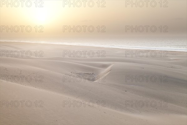 Sun in the mist of the sea above the sand dunes on Praia de Chaves Beach