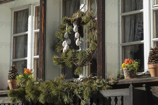 Wreath made of pine branches with eggs hanging from a window