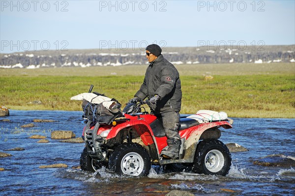 Man of the Inuit people riding a quad bike