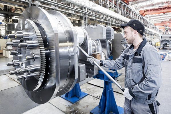 Employee tightening a screw plug on the crankshaft of a marine engine