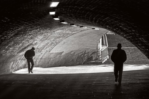 People in the light and shadow below the Liebknecht Bridge in Berlin Mitte