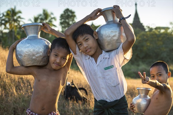 Boys carrying water in water containers made of aluminium