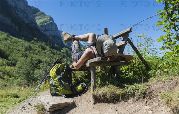 Female hiker lying on a bench