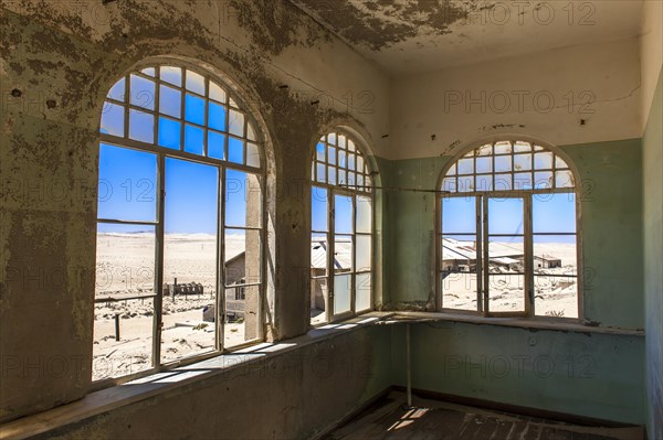 View through a window of an abandoned house in a former diamond miners settlement that is slowly covered by the sand of the Namib Desert