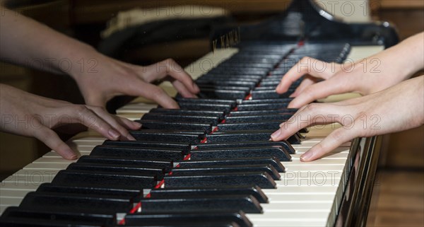 Two hands playing a piano and being reflected in the instrument