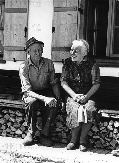 Old happy couple on the house bank in front of the farm