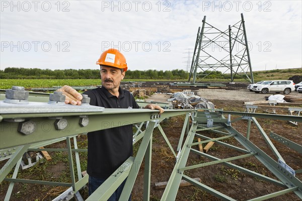 Engineer checking screw connections on segments of extra high-voltage pylons of a 380 kV extra-high voltage power line under construction