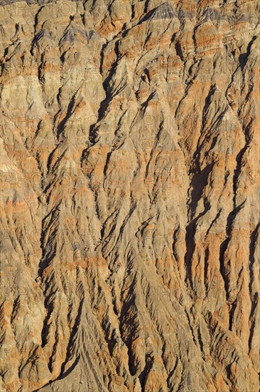 Exposed fissured bedrock of orange-colored conglomerate on the crater wall of Ubehebe Crater