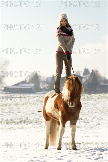 Woman wearing an Icelandic jumper standing on her painted Icelandic Horse