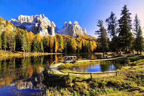 Autumn at Lake d'Antorno with a wooden bridge and the reflection of the Cadini Misurina Mountains