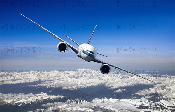 Cathay Pacific Boeing 777-367 ER in flight over mountains