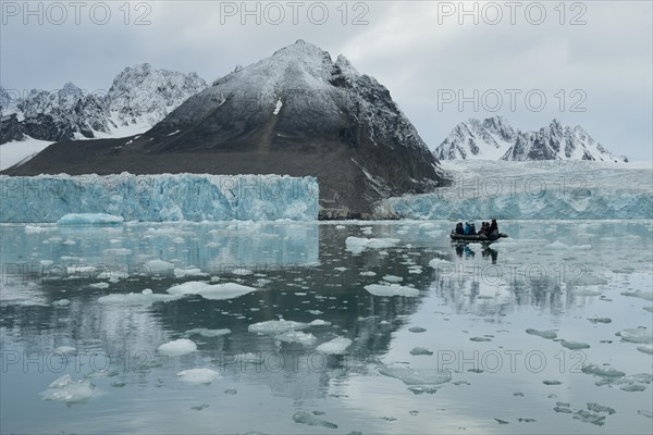 Tourists in a rubber dinghy in front of the rim of the Monacobreen Glacier