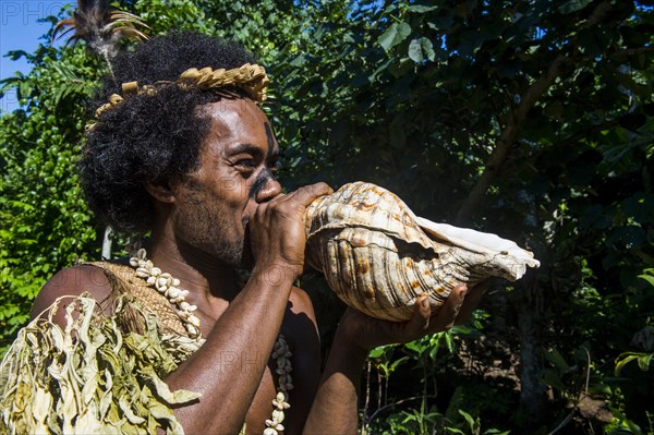 Man blowing in a giant shell