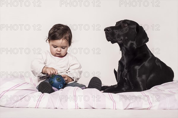 Big black mongrel lying next to a small child