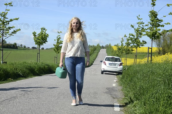 Woman walking away from her car carrying a petrol can