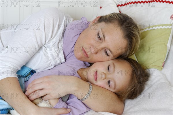 Mother and daughter cuddling in bed