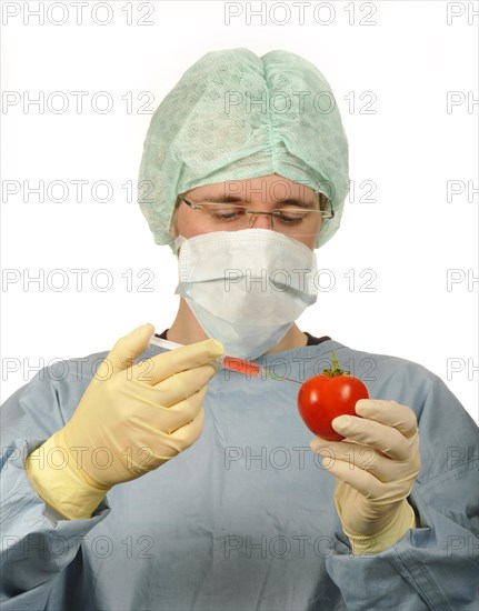 Chemist in sterile scrubs holding a syringe and a tomato