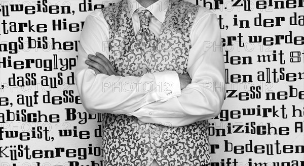Groom wearing a tie and a waistcoat standing in front of wall with lettering