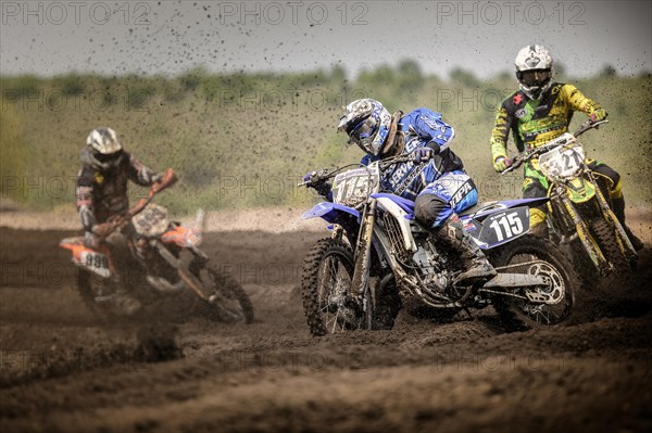 Three motocross riders on a track during a race