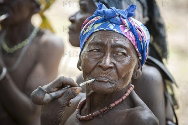 An elderly woman from the Koma people smoking a pipe