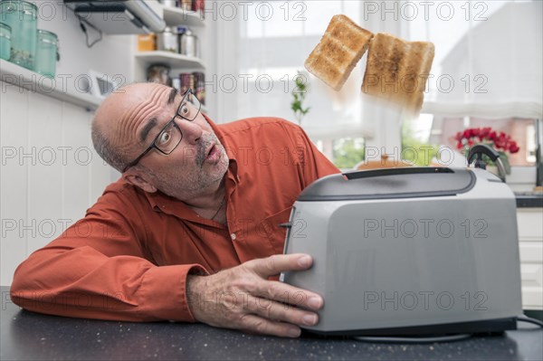 Man watching 2 slices of toast being ejected from a toaster