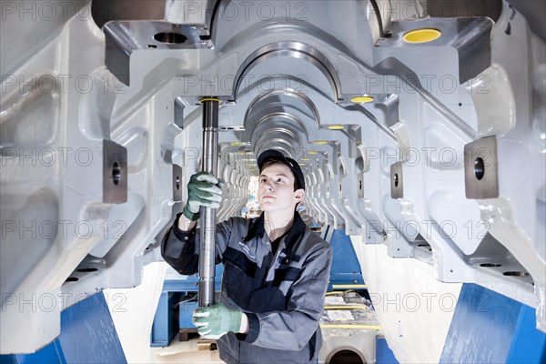 Employee fitting a tension rod into the engine frame of a marine engine